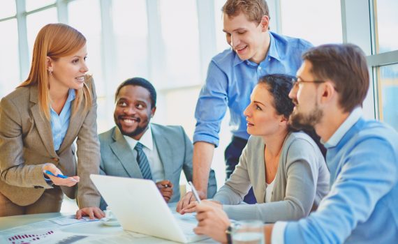 Group of employees looking at confident manager explaining her ideas at meeting